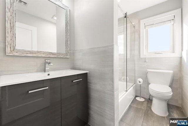 805 Fairview Ln, Fort Lee, NJ 07024 - bathroom featuring tile walls, vanity, toilet, and shower / bath combination with glass door
