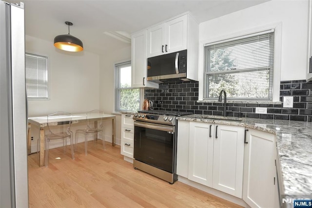 11-06 Marshall Rd, Fair Lawn, NJ 07410 - kitchen featuring appliances with stainless steel finishes, a sink, light wood-type flooring, tasteful backsplash, and white cabinetry