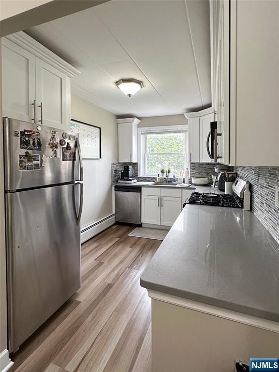 25 Jefferson St Unit 6E, Hackensack, NJ 07601 - kitchen with appliances with stainless steel finishes, baseboard heating, tasteful backsplash, light wood-style floors, and white cabinets