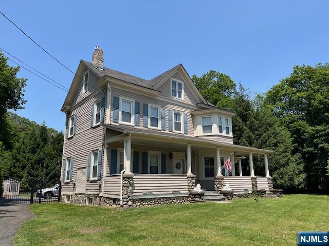 889 Circle Ave, Franklin Lakes, NJ 07417 - view of front facade with a chimney, a front lawn, and covered porch