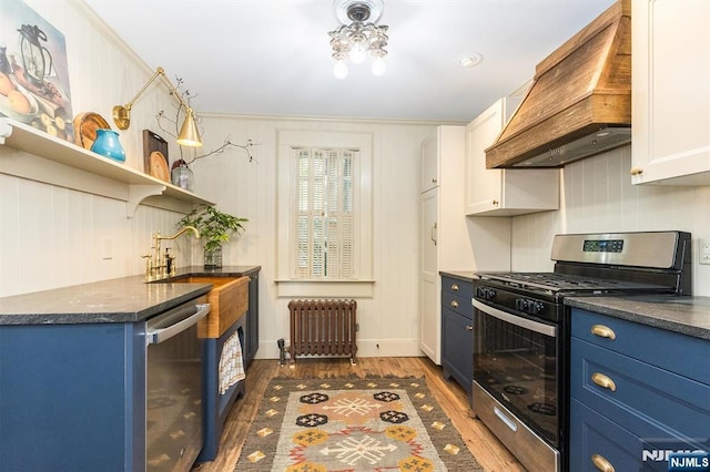 33 Ramapo Ave, Pompton Lakes, NJ 07442 - kitchen featuring radiator heating unit, stainless steel appliances, premium range hood, blue cabinets, and dark countertops