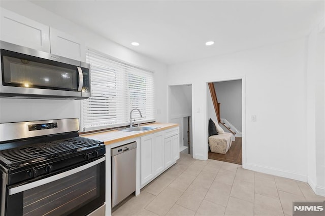 1146 Stasia St, Teaneck, NJ 07666 - kitchen featuring appliances with stainless steel finishes, white cabinets, wooden counters, light tile patterned flooring, and recessed lighting