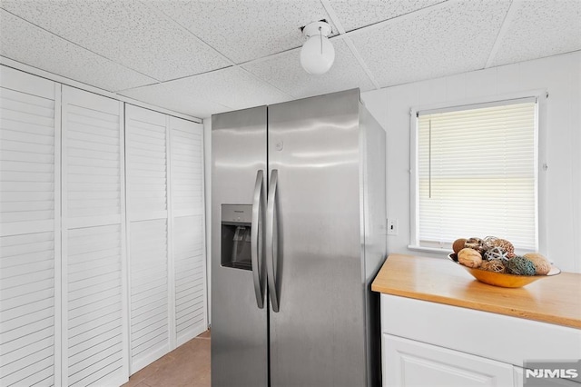 1146 Stasia St, Teaneck, NJ 07666 - kitchen featuring stainless steel refrigerator with ice dispenser, a drop ceiling, wood counters, and white cabinetry