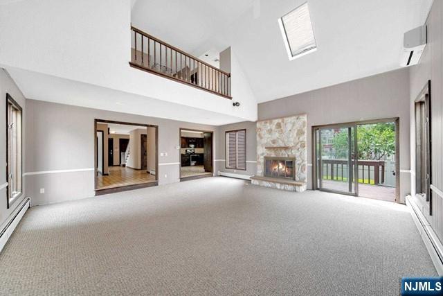 23 Bohnert Pl, Waldwick, NJ 07463 - unfurnished living room featuring high vaulted ceiling, carpet, a baseboard radiator, a wall mounted air conditioner, and a fireplace
