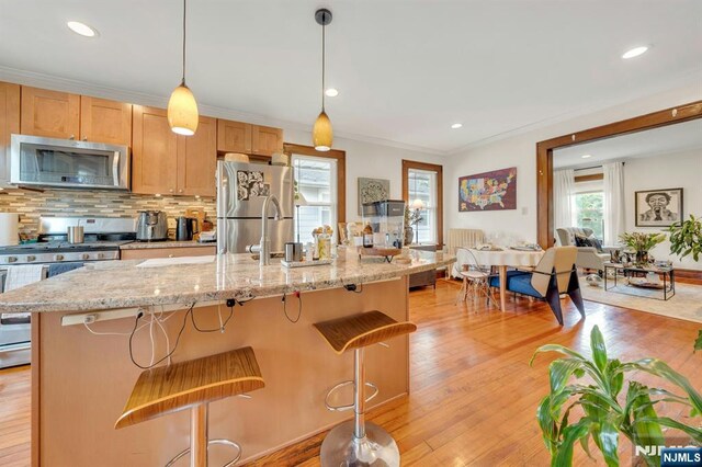 179 State St, Bloomfield, NJ 07003 - kitchen with appliances with stainless steel finishes, a kitchen breakfast bar, tasteful backsplash, light wood-type flooring, and recessed lighting