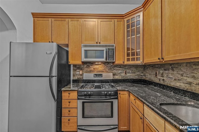 300 2nd St Unit 2, Jersey City, NJ 07302 - kitchen with stainless steel appliances, tasteful backsplash, dark stone counters, glass insert cabinets, and brown cabinets