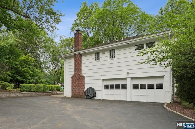 13 Stonewall Dr, Livingston, NJ 07039 - view of property exterior with asphalt driveway, a chimney, and a garage