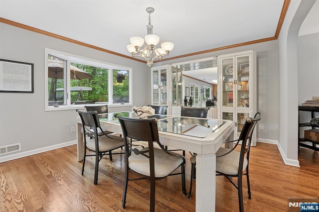 13 Stonewall Dr, Livingston, NJ 07039 - dining space featuring a chandelier, crown molding, arched walkways, baseboards, and light wood-style flooring