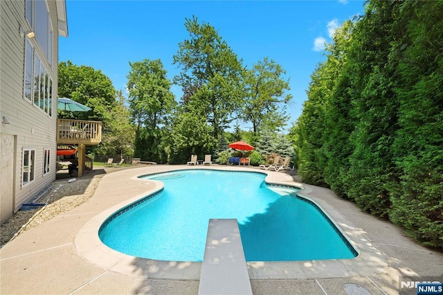 12 Woodland Ct, Wayne, NJ 07470 - swimming pool with a diving board, a patio area, view of wooded area, and a wooden deck