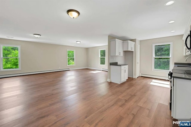 1582 Grnwd Lk, West Milford, NJ 07421 - kitchen with dark countertops, stove, white cabinetry, wood finished floors, and a baseboard radiator