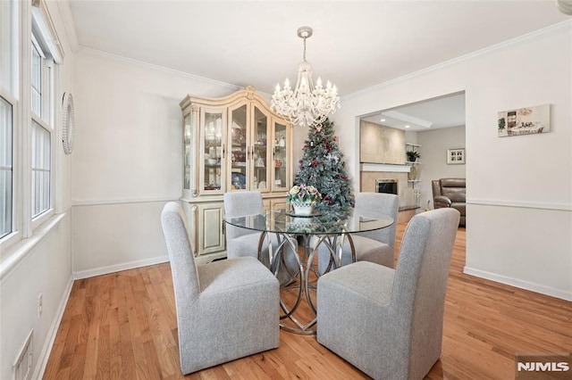 7 Meadow Ct, Midland Park, NJ 07432 - dining area featuring a chandelier, ornamental molding, healthy amount of natural light, a fireplace, and light wood-type flooring