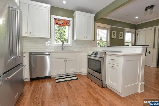  - kitchen with stainless steel appliances, a peninsula, white cabinets, backsplash, and crown molding