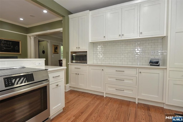  - kitchen with appliances with stainless steel finishes, crown molding, light countertops, white cabinets, and tasteful backsplash