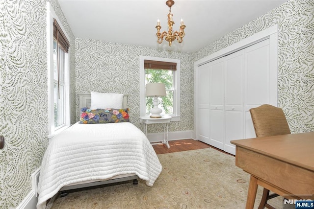  - bedroom with wallpapered walls, wood finished floors, a chandelier, and a closet