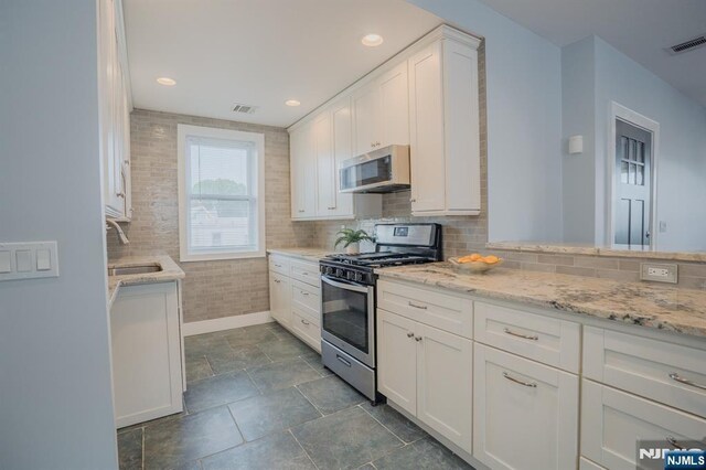 42 Berton Pl, Nutley, NJ 07110 - kitchen with appliances with stainless steel finishes, baseboards, white cabinetry, a sink, and light stone counters