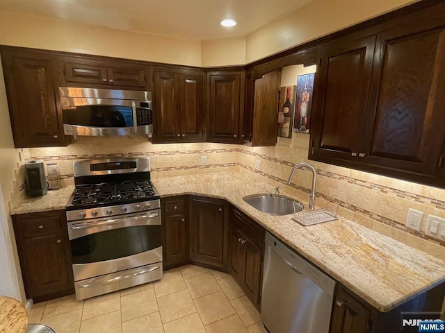 771 Stelton St, Teaneck, NJ 07666 - kitchen with stainless steel appliances, light tile patterned floors, dark brown cabinetry, decorative backsplash, and light stone countertops