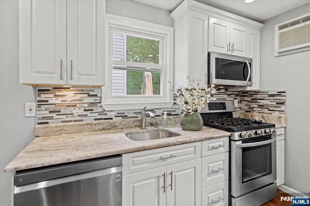 82 Elston St, Bloomfield, NJ 07003 - kitchen with stainless steel appliances, a sink, a wall unit AC, white cabinetry, and tasteful backsplash