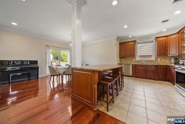 36-15 Garden View Ter, Fair Lawn, NJ 07410 - kitchen with ornate columns, appliances with stainless steel finishes, backsplash, a kitchen island, and ornamental molding