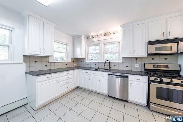85 Paulin Blvd, Leonia, NJ 07605 - kitchen featuring appliances with stainless steel finishes, a sink, a baseboard heating unit, decorative backsplash, and white cabinetry