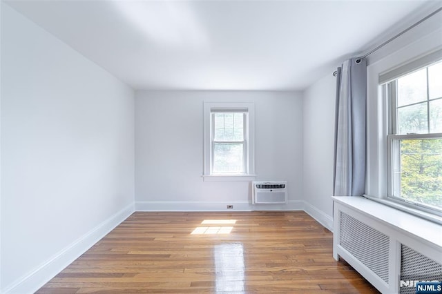 85 Paulin Blvd, Leonia, NJ 07605 - empty room with a wall mounted air conditioner, radiator, plenty of natural light, and wood finished floors