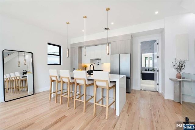 262 Webster Ave Unit 2, Jersey City, NJ 07307 - kitchen featuring stainless steel fridge, light wood-style floors, a kitchen breakfast bar, light countertops, and modern cabinets