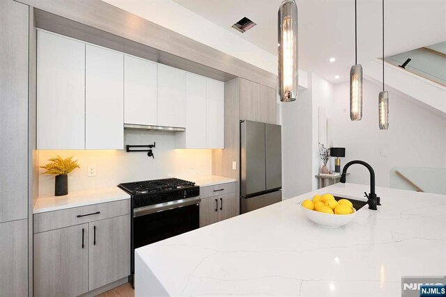 262 Webster Ave Unit 2, Jersey City, NJ 07307 - kitchen featuring freestanding refrigerator, gas stove, light stone counters, pendant lighting, and modern cabinets