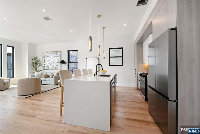 262 Webster Ave Unit 2, Jersey City, NJ 07307 - kitchen with freestanding refrigerator, modern cabinets, range with gas stovetop, a kitchen breakfast bar, and light wood-style flooring