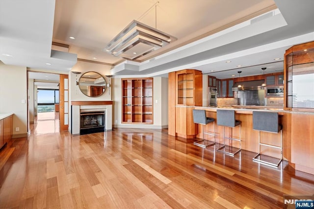 200 Old Palisade Unit Ph4/5, Fort Lee, NJ 07024 - kitchen featuring appliances with stainless steel finishes, light wood finished floors, glass insert cabinets, extractor fan, and a kitchen breakfast bar