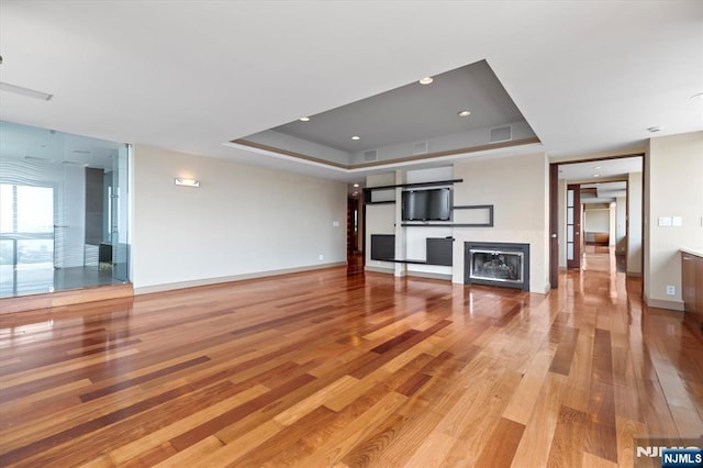 200 Old Palisade Unit Ph4/5, Fort Lee, NJ 07024 - unfurnished living room featuring light wood-style flooring, a glass covered fireplace, a raised ceiling, and recessed lighting