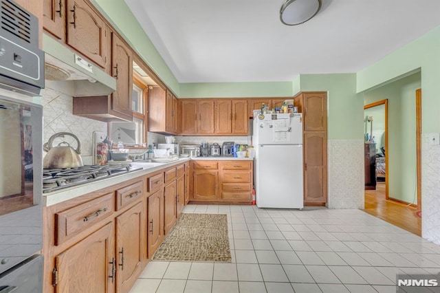 15 Jersey St, East Rutherford, NJ 07073 - kitchen with freestanding refrigerator, stainless steel gas stovetop, light countertops, under cabinet range hood, and wainscoting