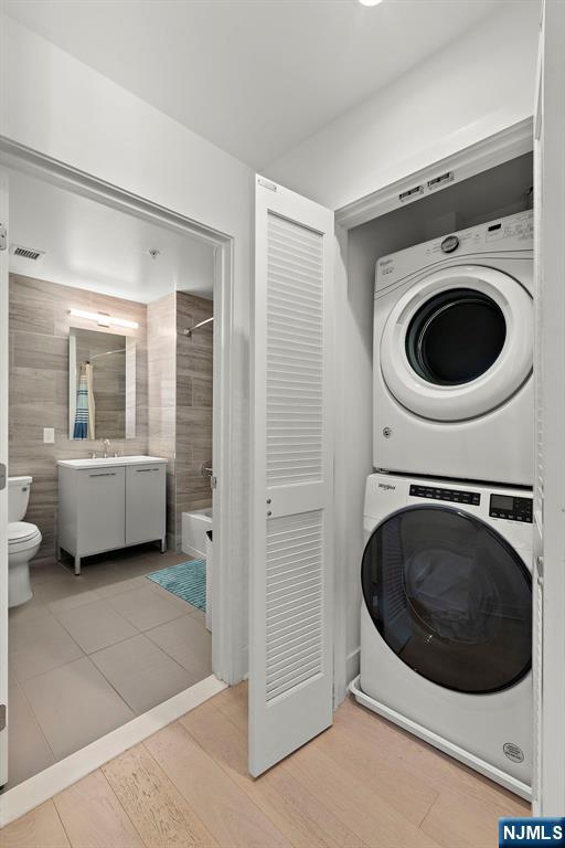 1400 Hudson St Unit 730, Hoboken, NJ 07030 - washroom featuring stacked washer and clothes dryer and light wood finished floors