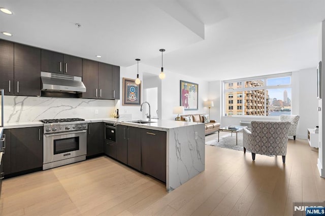 1400 Hudson St Unit 730, Hoboken, NJ 07030 - kitchen with under cabinet range hood, high end range, open floor plan, light wood-style flooring, and a peninsula