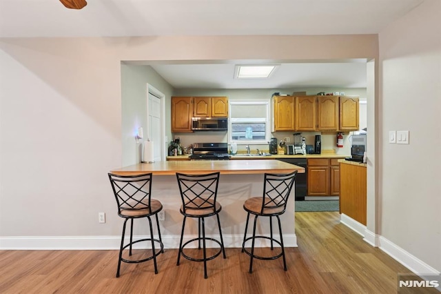 4 Lenape Trl, Wayne, NJ 07470 - kitchen with appliances with stainless steel finishes, a breakfast bar area, a sink, and light wood-type flooring