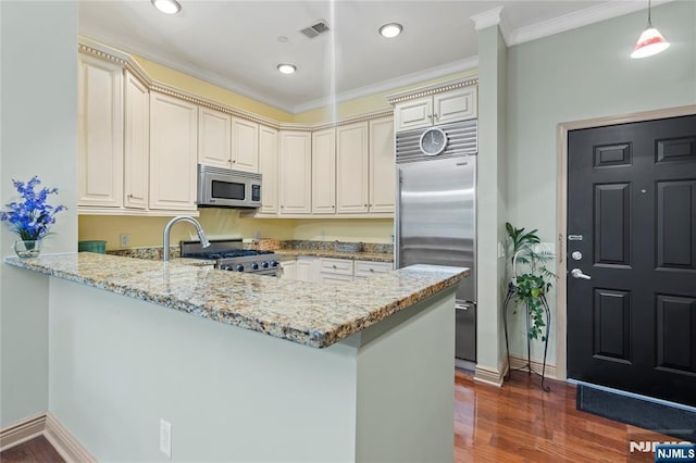 7400 River Rd Unit 120, North Bergen, NJ 07047 - kitchen featuring appliances with stainless steel finishes, cream cabinets, a peninsula, light stone countertops, and dark wood-style floors