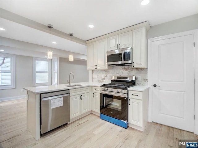 138 Willow St, Bloomfield, NJ 07003 - kitchen featuring appliances with stainless steel finishes, light countertops, light wood finished floors, a peninsula, and decorative backsplash