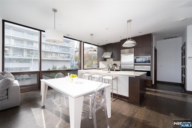 9 Somerset Ln Unit 201, Edgewater, NJ 07020 - kitchen with built in appliances, exhaust hood, light countertops, and dark wood-style floors