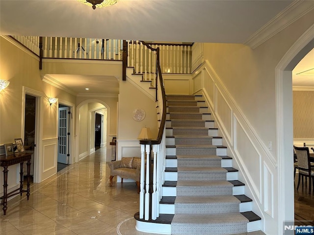 591 Warwick Ave, Teaneck, NJ 07666 - staircase featuring arched walkways, a decorative wall, crown molding, a high ceiling, and wainscoting