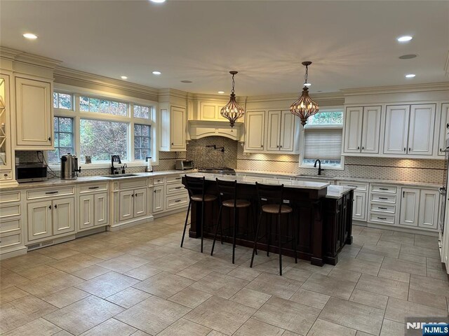 591 Warwick Ave, Teaneck, NJ 07666 - kitchen featuring tasteful backsplash, a center island, a chandelier, ornamental molding, and recessed lighting