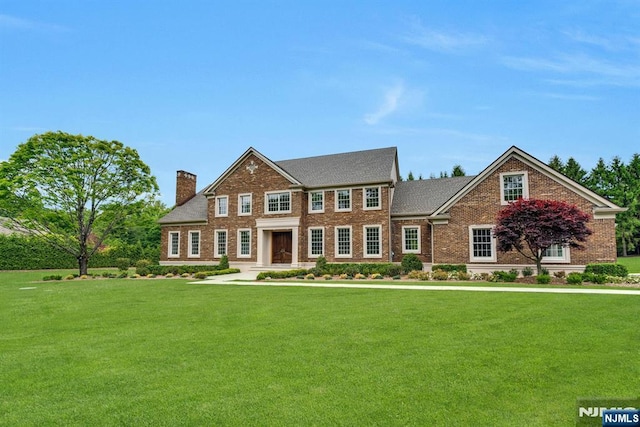 333 Mill Rd, Saddle River, NJ 07458 - colonial inspired home featuring brick siding, a chimney, and a front lawn