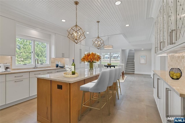 333 Mill Rd, Saddle River, NJ 07458 - kitchen with white cabinets, recessed lighting, a center island, backsplash, and light stone counters
