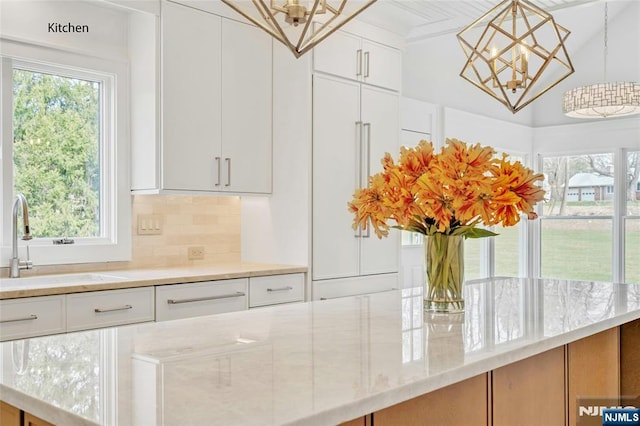 333 Mill Rd, Saddle River, NJ 07458 - kitchen with a chandelier, light stone counters, white cabinets, and decorative backsplash