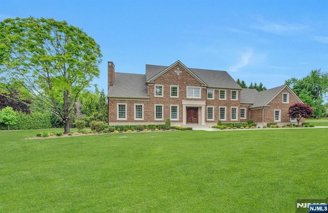 333 Mill Rd, Saddle River, NJ 07458 - georgian-style home featuring a chimney, a front yard, and brick siding