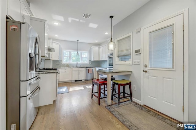 178 Arthur St, Hillsdale, NJ 07642 - kitchen featuring stainless steel appliances, a breakfast bar, white cabinets, light wood finished floors, and hanging light fixtures