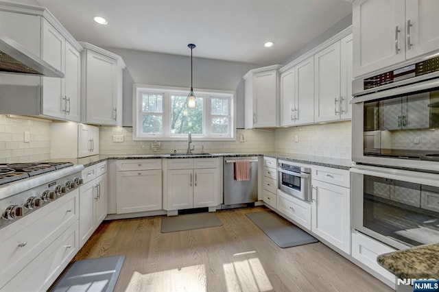 178 Arthur St, Hillsdale, NJ 07642 - kitchen featuring appliances with stainless steel finishes, wall chimney range hood, white cabinets, light wood finished floors, and recessed lighting