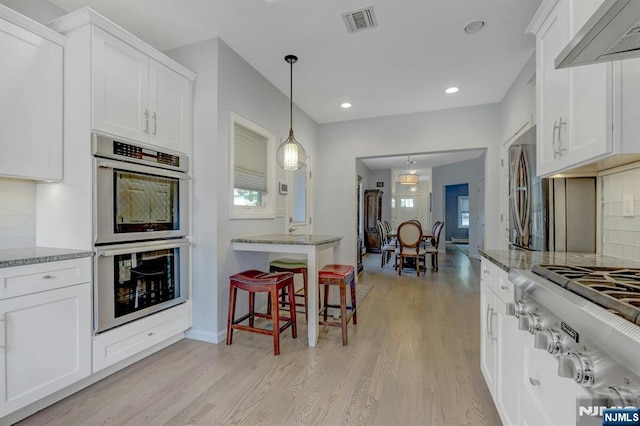 178 Arthur St, Hillsdale, NJ 07642 - kitchen featuring stainless steel appliances, wall chimney range hood, light wood-style floors, tasteful backsplash, and white cabinetry