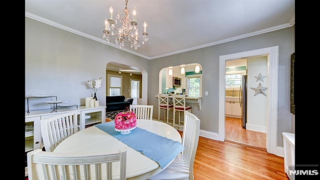 118 High St, Nutley, NJ 07110 - dining area featuring arched walkways, light wood finished floors, crown molding, and a chandelier