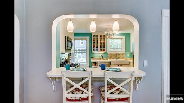 118 High St, Nutley, NJ 07110 - kitchen featuring stainless steel appliances, arched walkways, glass insert cabinets, and a peninsula