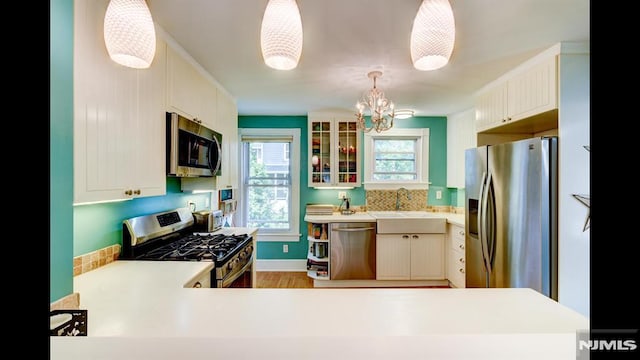 118 High St, Nutley, NJ 07110 - kitchen featuring appliances with stainless steel finishes, a chandelier, wood finished floors, light countertops, and glass insert cabinets