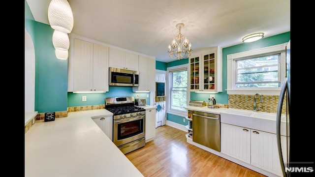 118 High St, Nutley, NJ 07110 - kitchen with appliances with stainless steel finishes, a chandelier, glass insert cabinets, and light countertops
