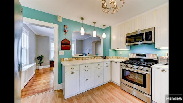 118 High St, Nutley, NJ 07110 - kitchen featuring appliances with stainless steel finishes, light countertops, light wood-type flooring, hanging light fixtures, and a chandelier